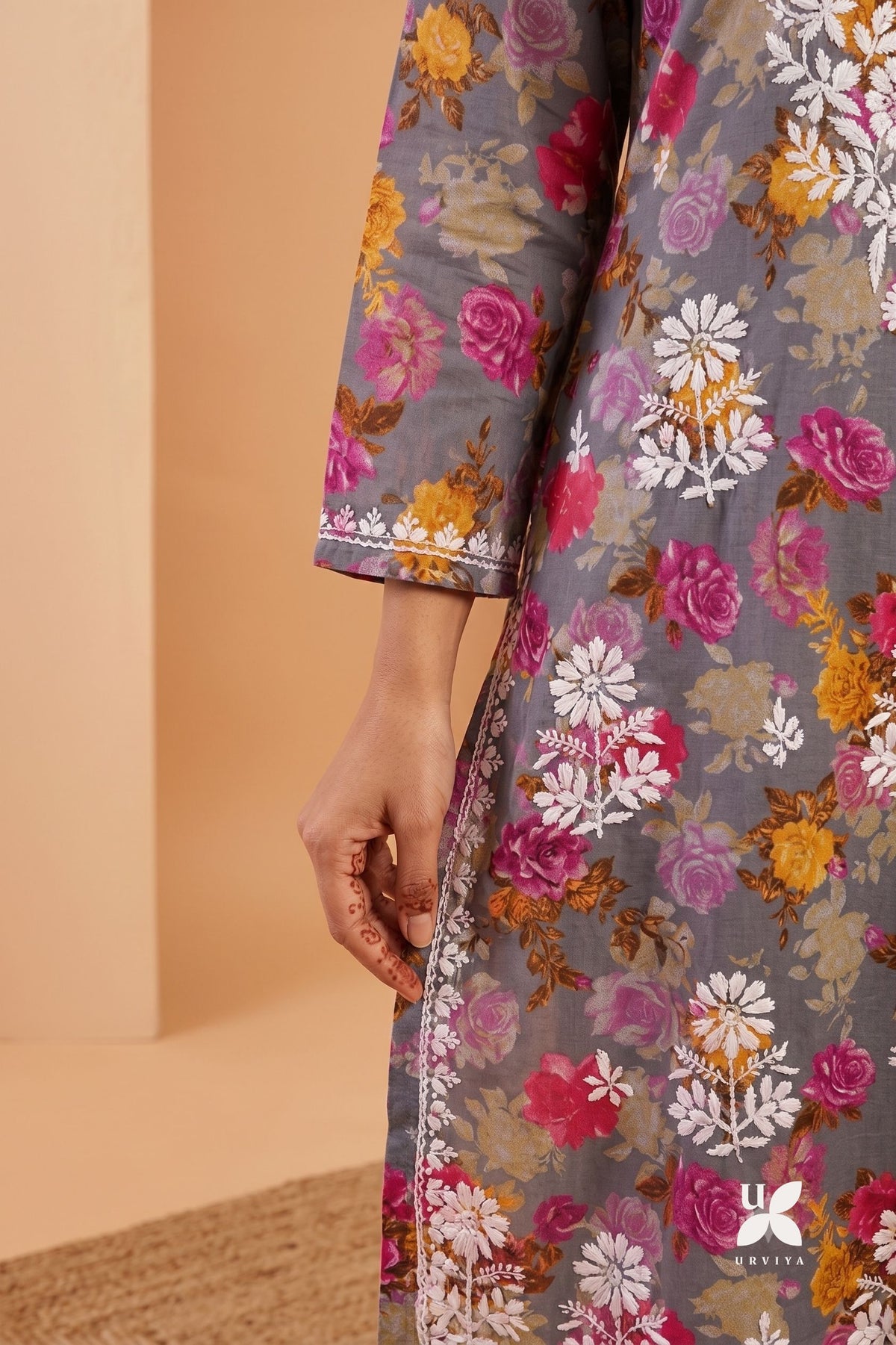 Close-up of a person wearing a gray floral printed kurta with pink, white, and yellow flowers, showing the fabric pattern and sleeve detail.