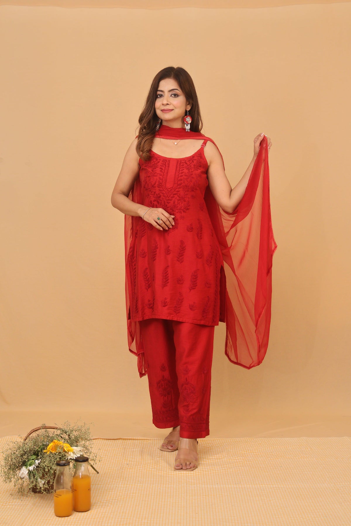 A woman models a red embroidered ethnic suit set consisting of a kurta, pants, and a dupatta against a solid beige backdrop. Red Chanderi Ghaaspatti Chikankari Spaghetti 2 Piece Set