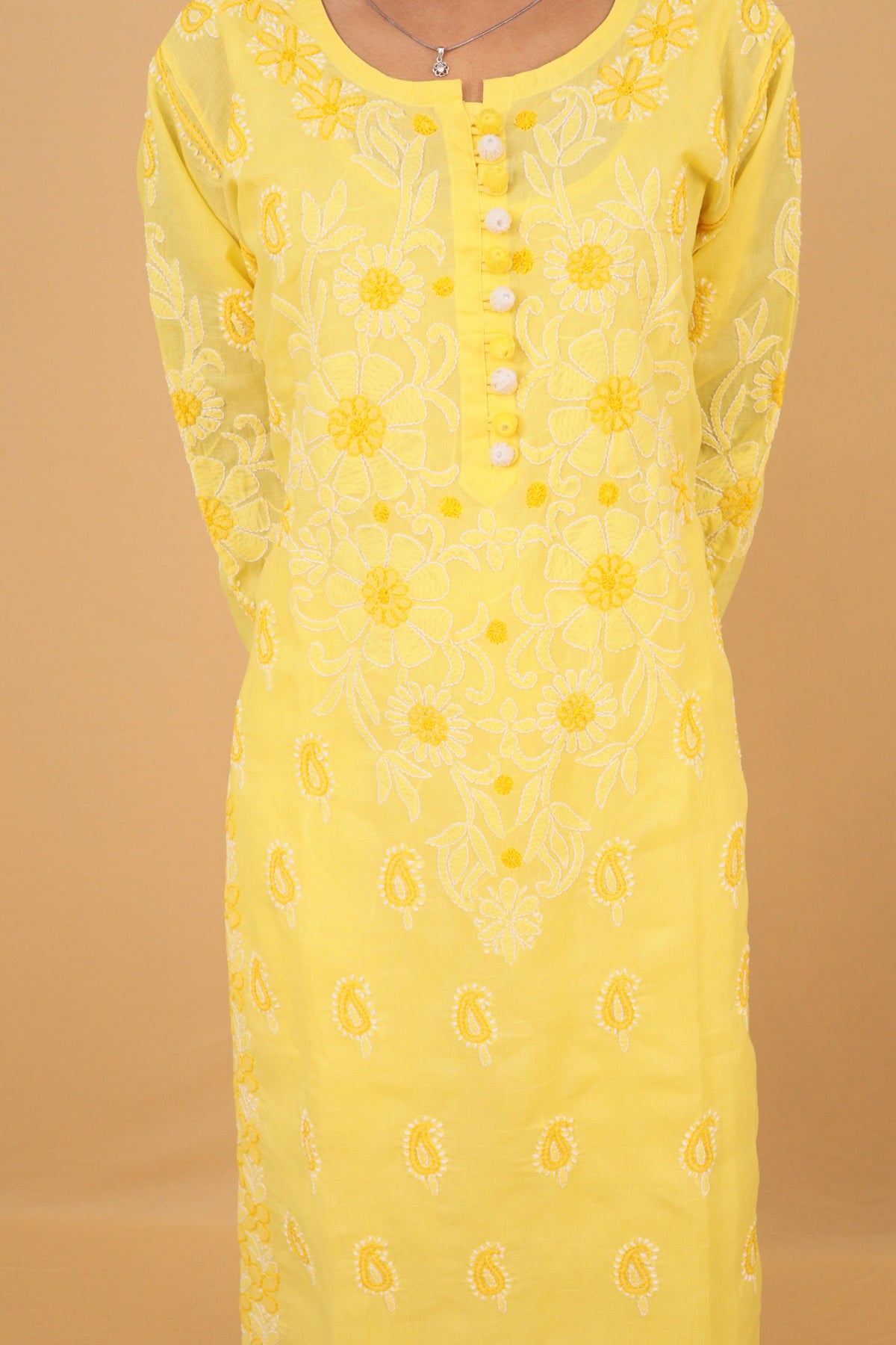 A yellow long-sleeve tunic dress with white floral and paisley embroidery, featuring a buttoned front neckline, shown against a solid beige background. Yellow Cotton Chikankari Bakhiya Kurti with White Pants & Dupatta 3 Piece Set